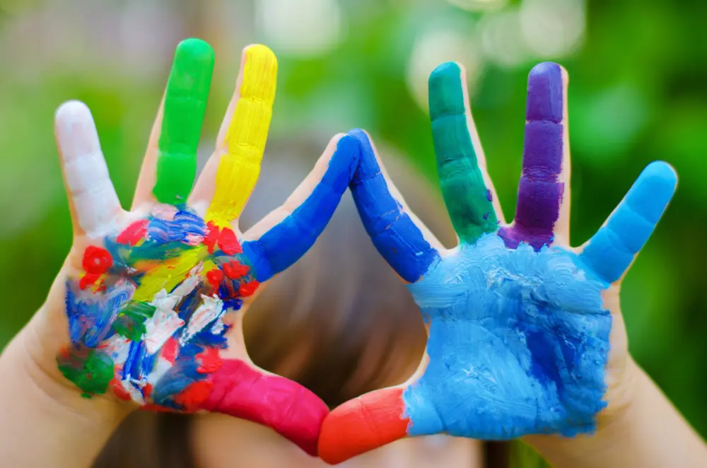 Children's hands painted with colorful paint.